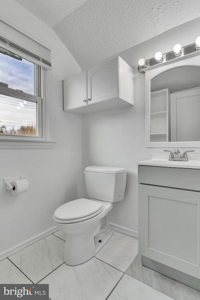 bathroom featuring vanity, vaulted ceiling, a textured ceiling, and toilet