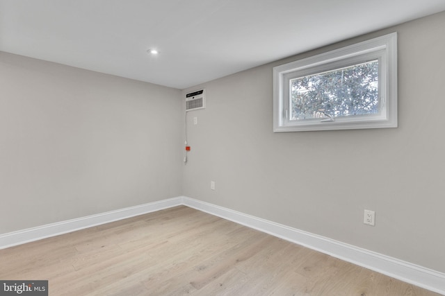 empty room with an AC wall unit and light wood-type flooring