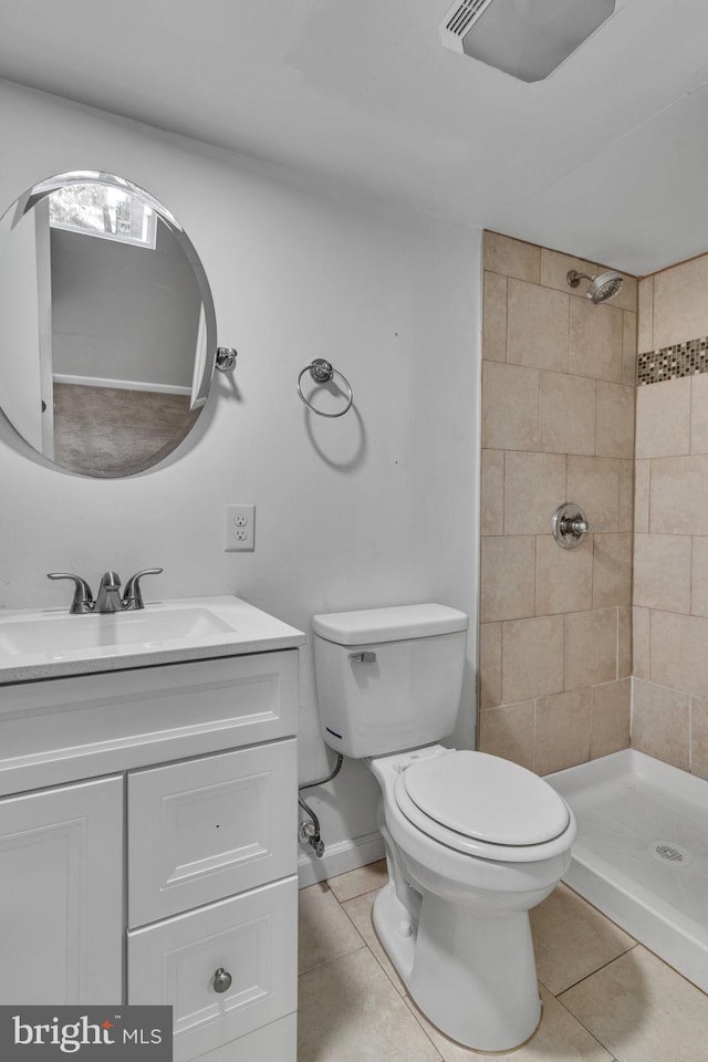 bathroom featuring tile patterned flooring, vanity, toilet, and a tile shower