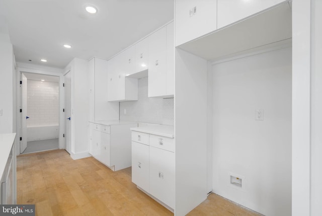 kitchen with decorative backsplash, white cabinets, and light hardwood / wood-style floors