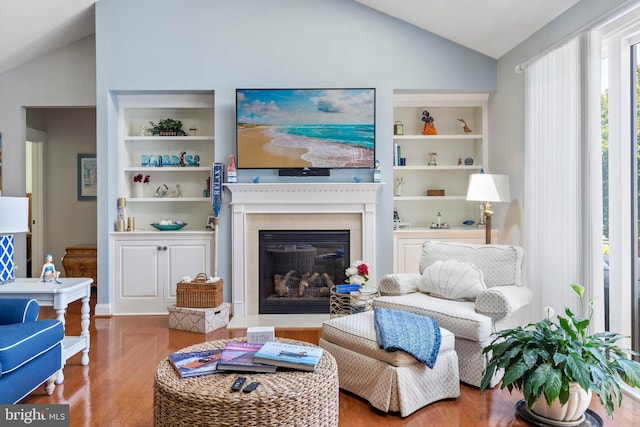 living area with lofted ceiling, built in shelves, and wood-type flooring