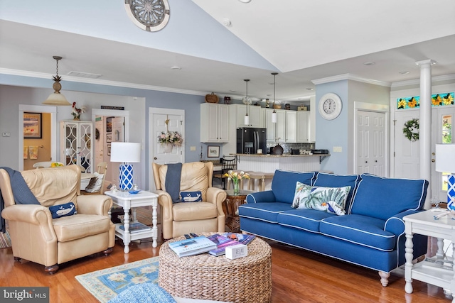 living room with lofted ceiling, hardwood / wood-style floors, crown molding, and ornate columns