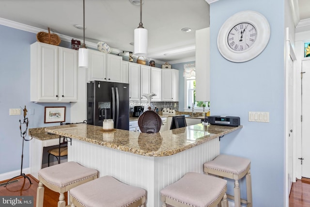 kitchen featuring light stone countertops, black fridge with ice dispenser, kitchen peninsula, and white cabinets