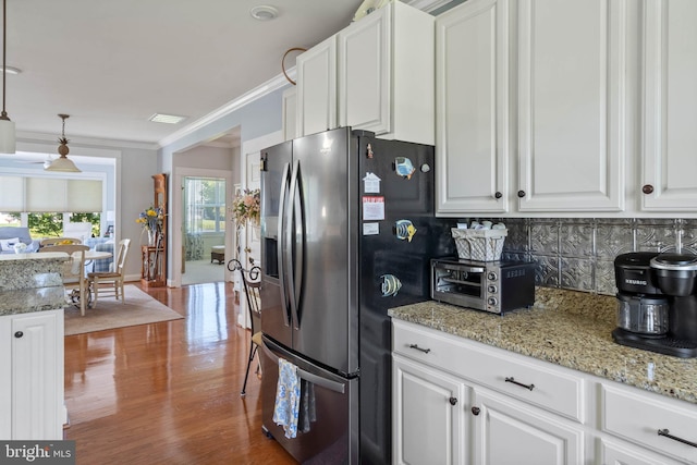 kitchen with pendant lighting, crown molding, stainless steel fridge, white cabinets, and decorative backsplash