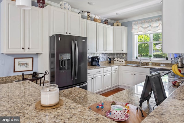 kitchen featuring sink, black fridge with ice dispenser, light stone countertops, and white cabinets