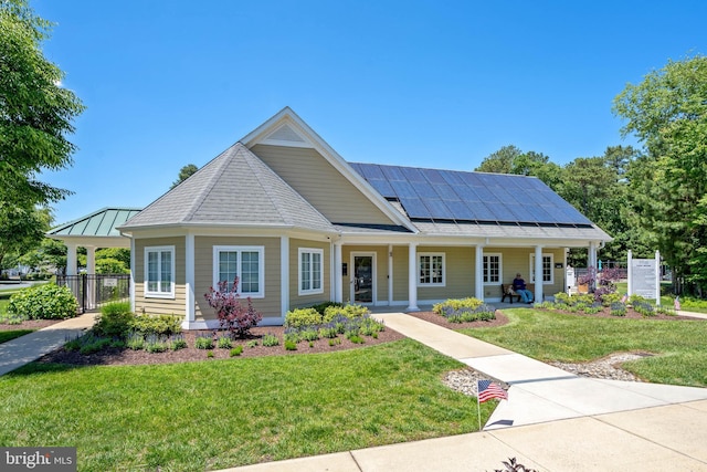 view of front of home with covered porch, a front yard, and solar panels