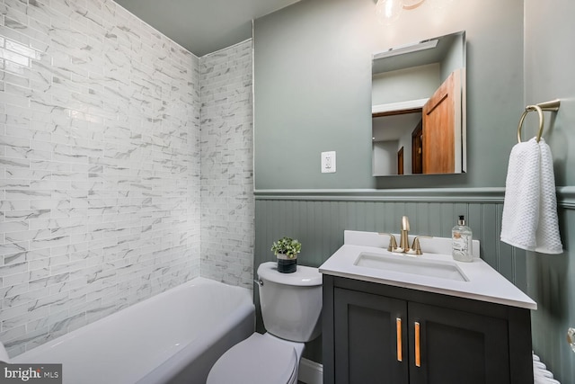 bathroom with shower / bathing tub combination, toilet, wainscoting, and vanity