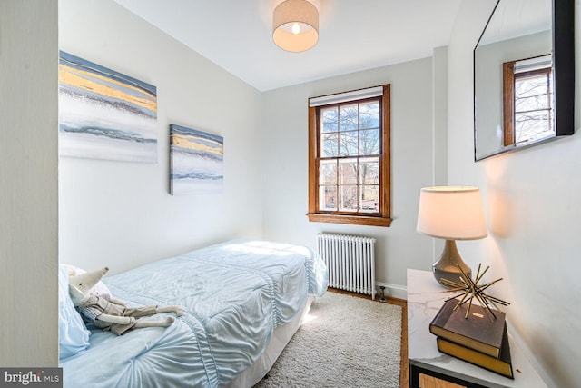 bedroom featuring radiator, wood finished floors, and baseboards