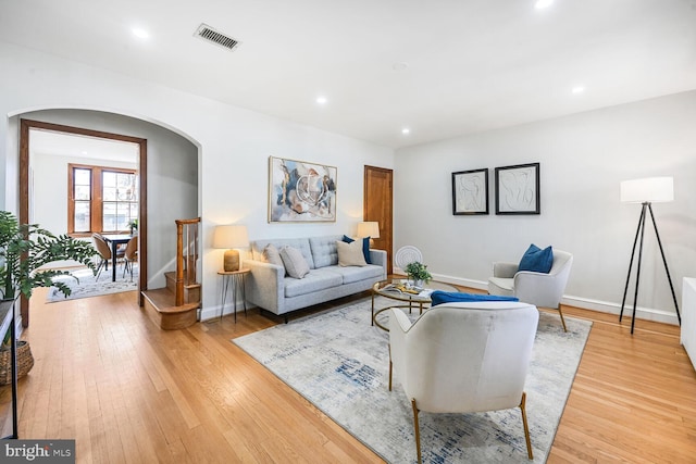 living room featuring arched walkways, visible vents, recessed lighting, and light wood-style floors