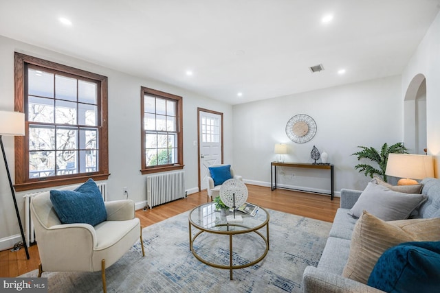 living area featuring visible vents, recessed lighting, radiator heating unit, and wood finished floors