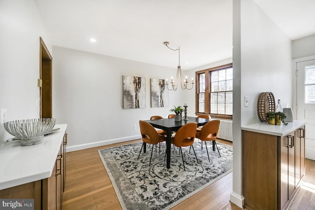 dining room with a wealth of natural light, an inviting chandelier, baseboards, and light wood-style floors