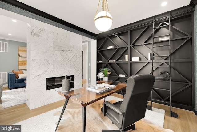 office featuring a fireplace, light wood-type flooring, and ornamental molding