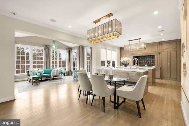 dining room with light hardwood / wood-style flooring, crown molding, and sink