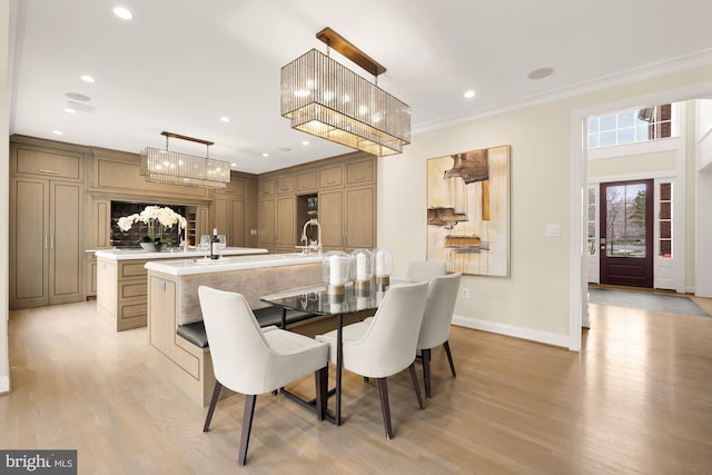 dining area featuring light wood-type flooring, crown molding, and sink