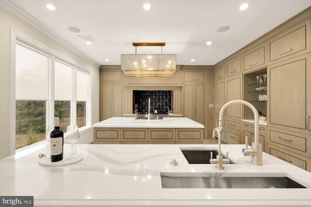 kitchen featuring decorative light fixtures, plenty of natural light, a kitchen island with sink, and crown molding