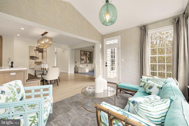 living room with vaulted ceiling, dark wood-type flooring, crown molding, sink, and an inviting chandelier