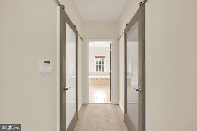 corridor with a barn door and light colored carpet