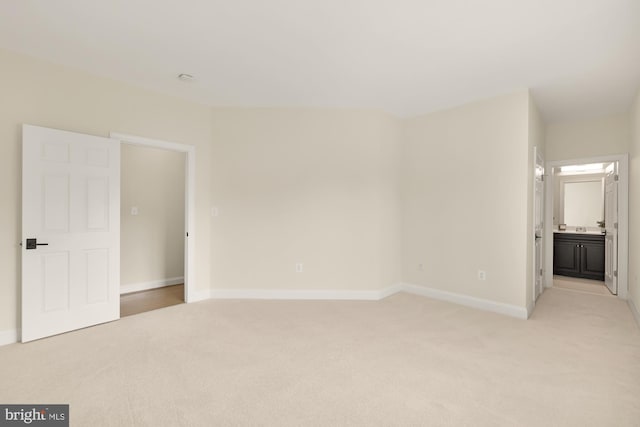 unfurnished bedroom with light carpet and connected bathroom