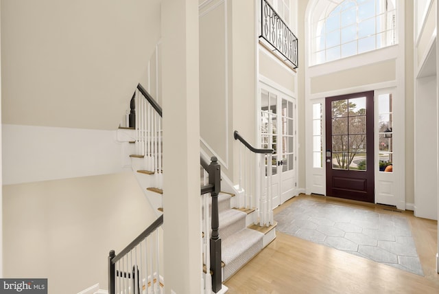 foyer entrance featuring a towering ceiling and light hardwood / wood-style flooring