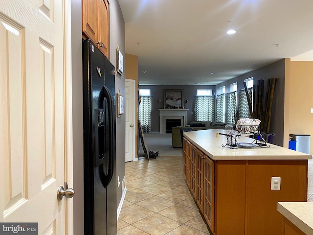 kitchen with a center island, black fridge with ice dispenser, and light tile patterned floors