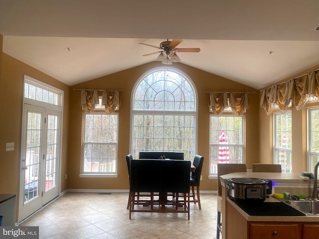 dining space with ceiling fan, sink, light tile patterned flooring, and vaulted ceiling