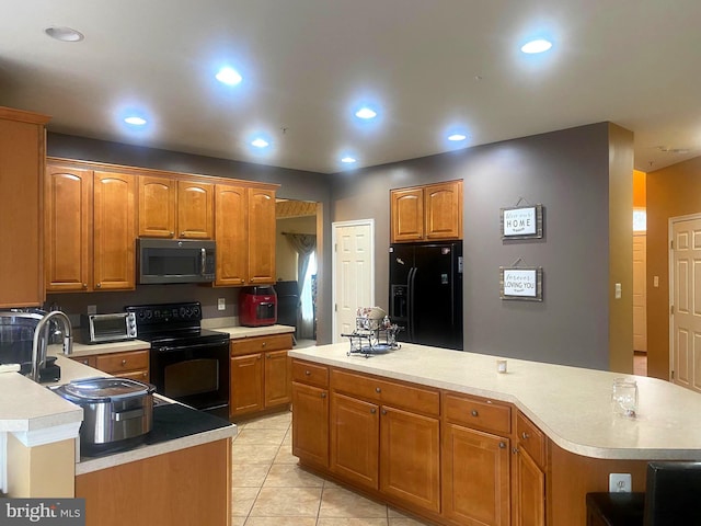 kitchen featuring black appliances, a center island, light tile patterned flooring, and sink