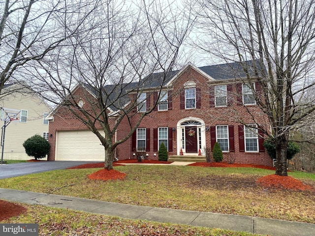 colonial inspired home with a front lawn and a garage