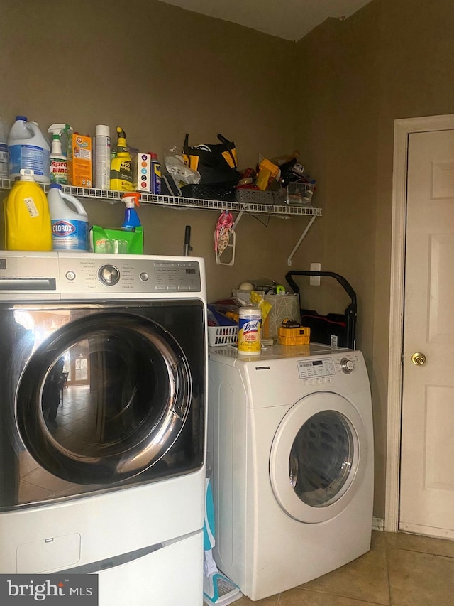 clothes washing area with washing machine and clothes dryer and tile patterned floors