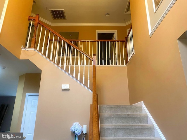 stairs with crown molding and a towering ceiling