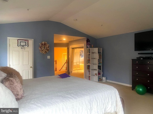 carpeted bedroom featuring vaulted ceiling and ensuite bath