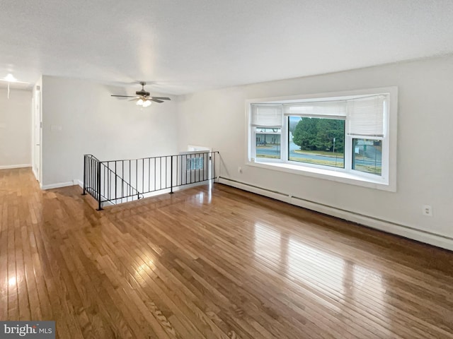 unfurnished room featuring hardwood / wood-style flooring, ceiling fan, baseboard heating, and a textured ceiling