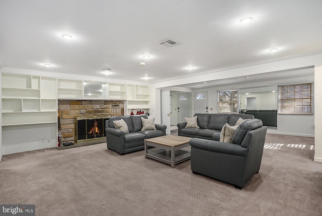 living room with a stone fireplace, light colored carpet, ornamental molding, and built in features