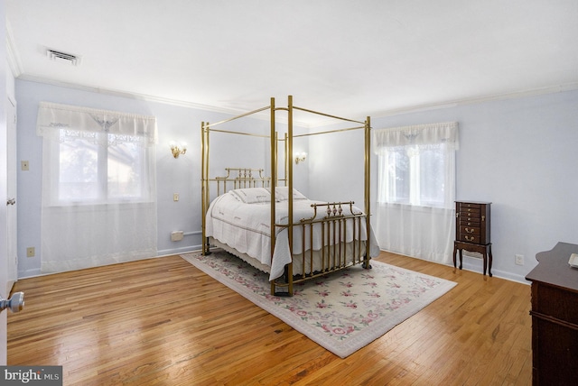 bedroom featuring wood-type flooring, multiple windows, and crown molding