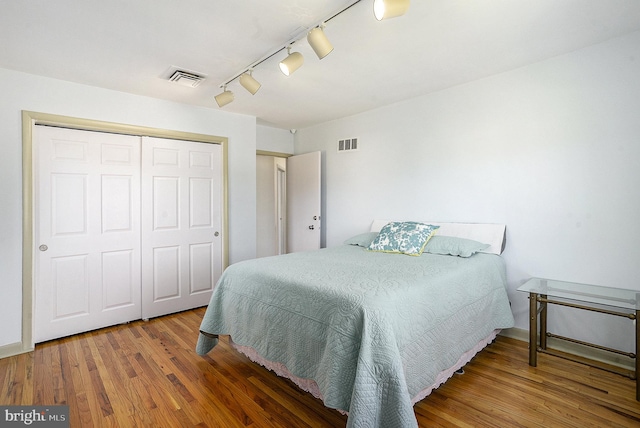 bedroom with hardwood / wood-style flooring, a closet, and track lighting