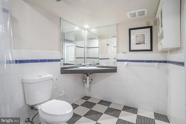 bathroom featuring toilet and tile walls