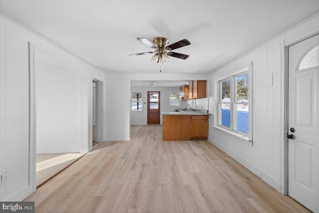 kitchen featuring kitchen peninsula, ceiling fan, sink, and light hardwood / wood-style floors