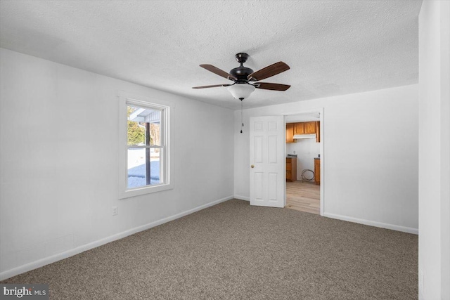 carpeted spare room featuring a textured ceiling and ceiling fan