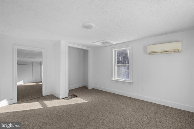 unfurnished bedroom with carpet flooring, a textured ceiling, a wall unit AC, and a closet