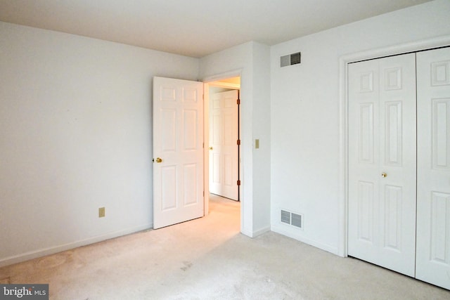 unfurnished bedroom featuring light colored carpet and a closet