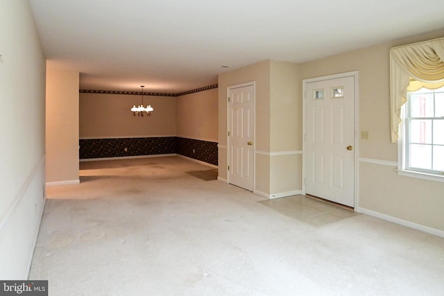 carpeted empty room featuring a chandelier