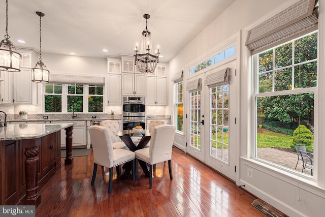 dining space with dark hardwood / wood-style flooring, an inviting chandelier, a wealth of natural light, and sink