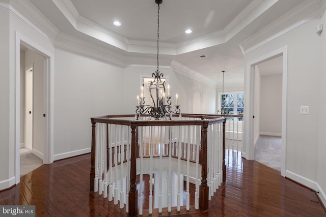 hall with a chandelier, dark hardwood / wood-style flooring, a raised ceiling, and crown molding