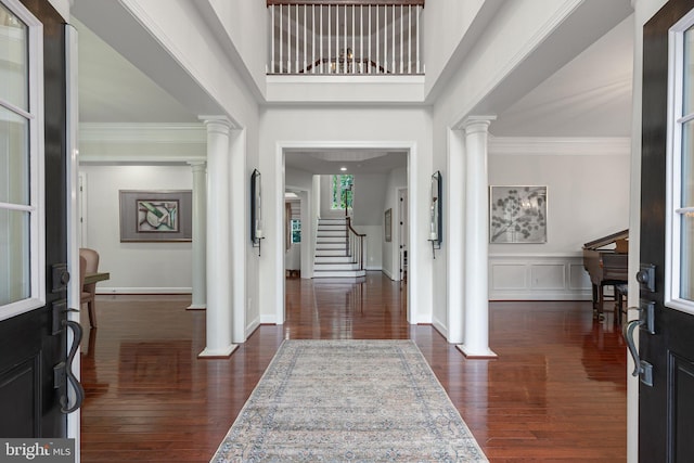 entryway featuring dark hardwood / wood-style floors, ornamental molding, and a high ceiling