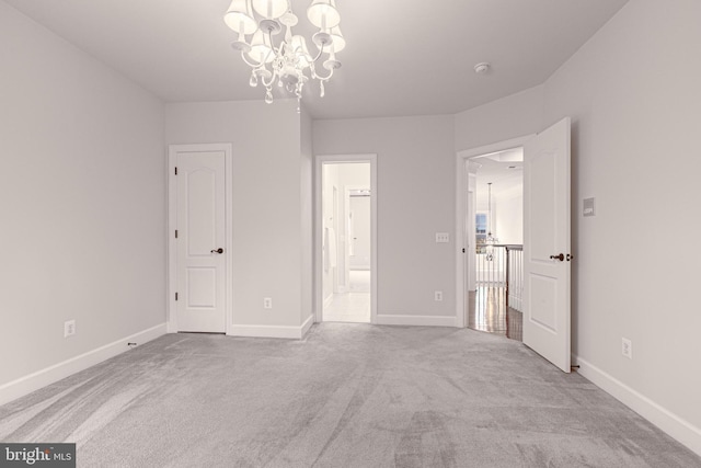 unfurnished bedroom featuring light carpet, connected bathroom, and an inviting chandelier