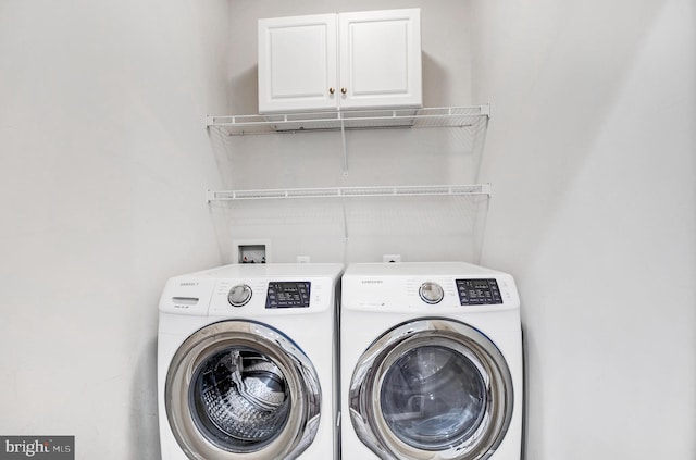 washroom with washer and dryer and cabinets