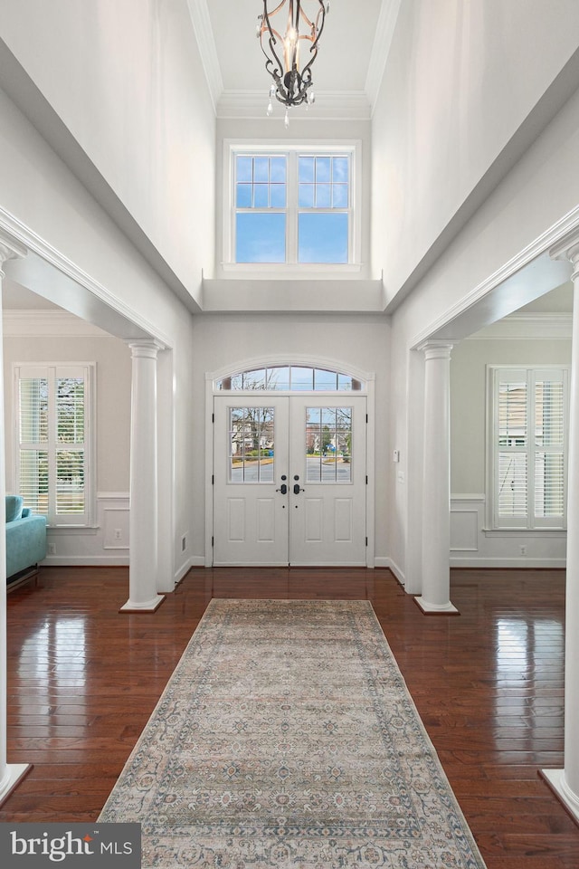 entrance foyer featuring crown molding, a towering ceiling, dark wood-type flooring, and a chandelier