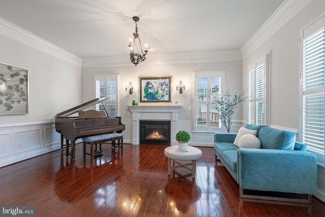 sitting room featuring a healthy amount of sunlight, ornamental molding, dark wood-type flooring, and an inviting chandelier