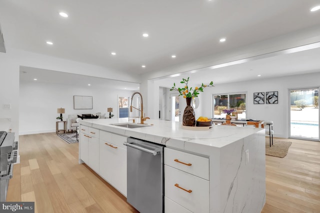 kitchen featuring a center island with sink, stainless steel dishwasher, sink, white cabinetry, and light stone counters