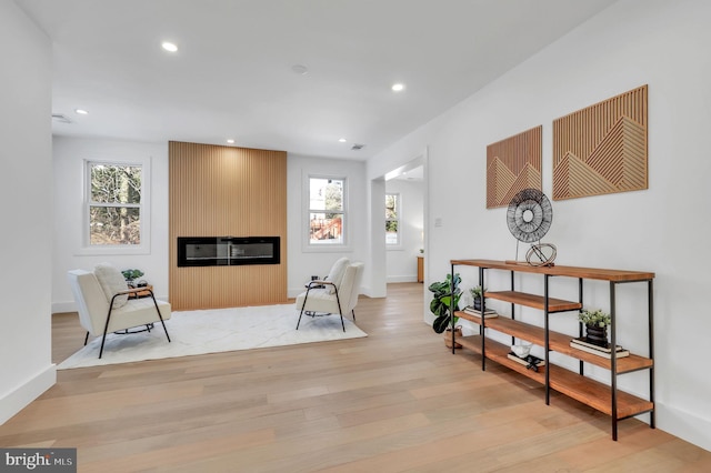 living area featuring plenty of natural light, a large fireplace, and light hardwood / wood-style flooring