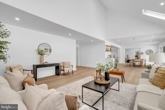 living room with high vaulted ceiling and light wood-type flooring